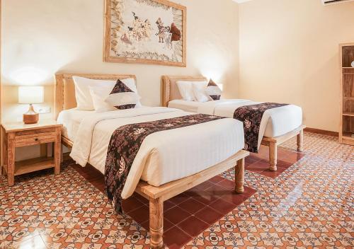 a hotel room with two beds and two tables at Shanaya Resort Malang in Malang