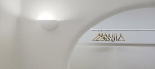 a bathroom with a white wall and a rack with utensils at Mystic Villas Koufonisi in Koufonisia