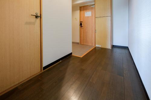 an empty hallway with wooden floors and doors at Miyazaki Mango Hotel in Miyazaki