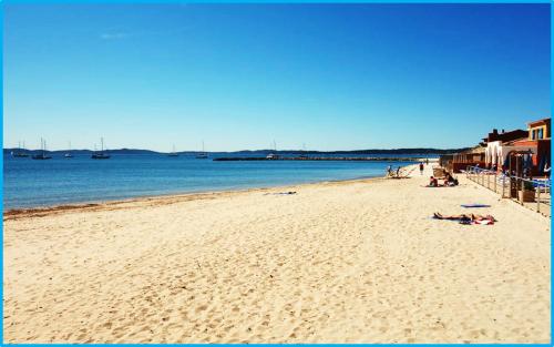 a beach with people laying on the sand and the water at Port Hyeres Duplex plein Sud 200 M2 et 100 M2 de terrasse in Hyères