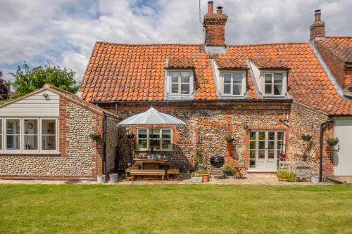 a brick house with a table and an umbrella at Gable End in Great Snoring