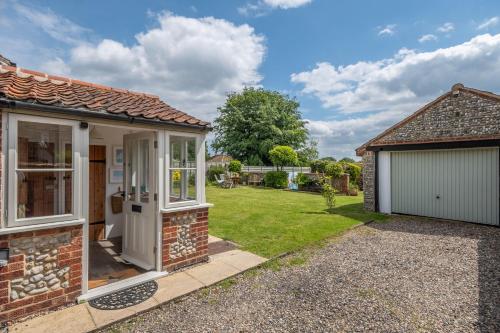 a cottage with a garage and a lawn at Gable End in Great Snoring