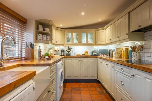 a kitchen with white cabinets and wooden counter tops at Gable End in Great Snoring