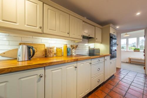 a kitchen with white cabinets and a wooden counter top at Gable End in Great Snoring