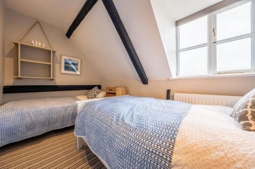 a attic bedroom with two beds and two windows at Gable End in Great Snoring