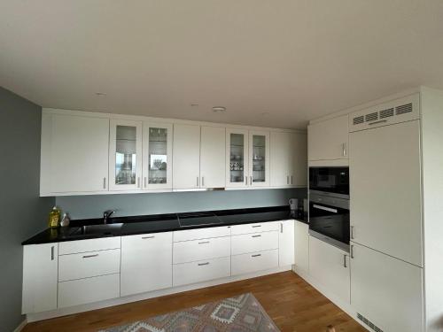 a kitchen with white cabinets and black counter tops at En perle på Gjøvik, nær populær strand ved Mjøsa in Gjøvik