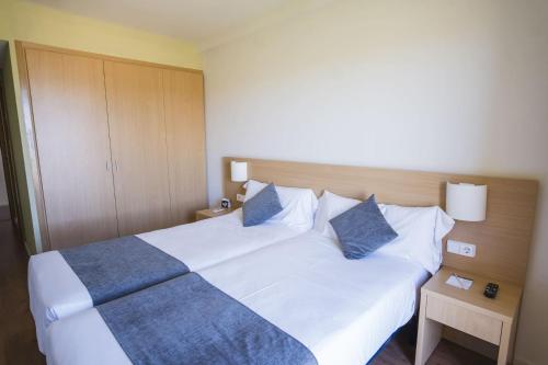 a bedroom with a large white bed with blue pillows at Hotel Alda Triskel in Sos del Rey Católico