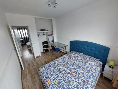 - une chambre avec un lit bleu et une table dans l'établissement le Pradeau - T3 panorama Pyrénées, à Tarbes