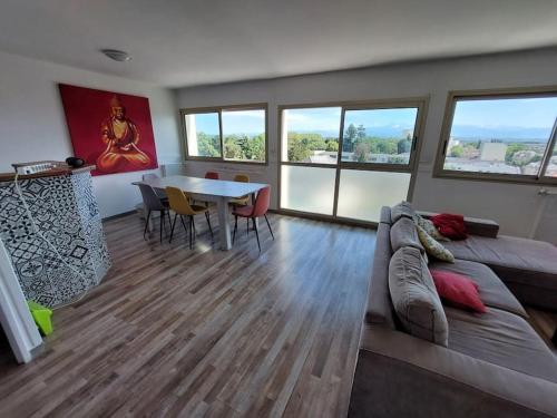 - un salon avec un canapé, une table et des fenêtres dans l'établissement le Pradeau - T3 panorama Pyrénées, à Tarbes