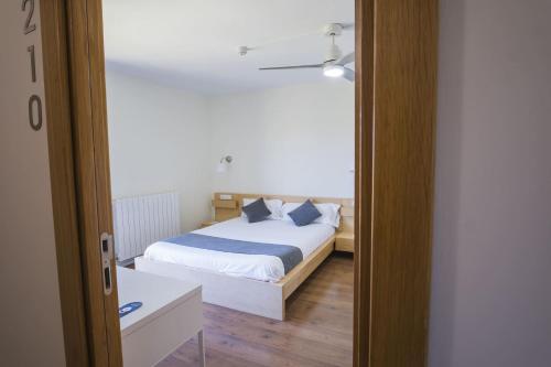 a bedroom with a white bed with blue pillows at Hotel Alda Triskel in Sos del Rey Católico