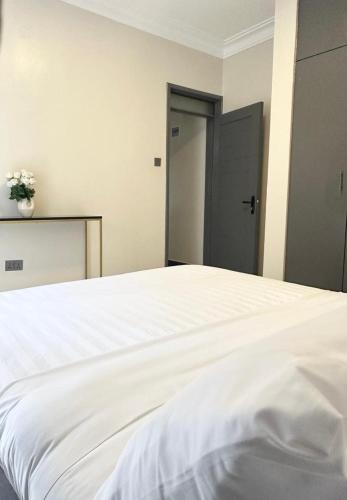 a white bed in a room with a door at Livluxe Apartments 7 in Kampala