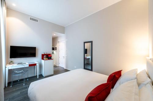 a bedroom with a large white bed with red pillows at Corte Novella Hotel & Residence in Brescia
