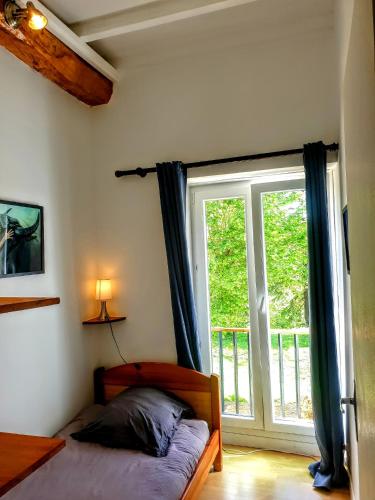 a bedroom with a bed and a large window at La douce étable - 25 minutes d'Agen in Port-Sainte-Marie