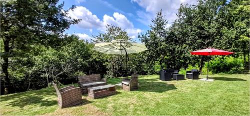 a park with two benches and an umbrella at La douce étable - 25 minutes d'Agen in Port-Sainte-Marie