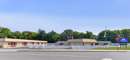 een lege straat voor een gebouw met een stopbord bij Americas Best Value Inn - Port Jefferson Station - Long Island in Port Jefferson Station