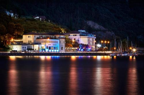 a large building next to a body of water at night at Hotel Paradiso Conca d'Oro in Nago-Torbole
