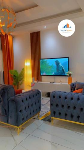 a living room with two blue couches and a flat screen tv at Merkur Apparts in Yaoundé