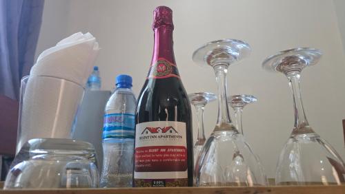 a bottle of wine sitting next to wine glasses at Silent Inn Apartments in Arusha