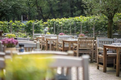 a row of tables and chairs in a garden at MUNTE - Wellnesshotel am Stadtwald in Bremen