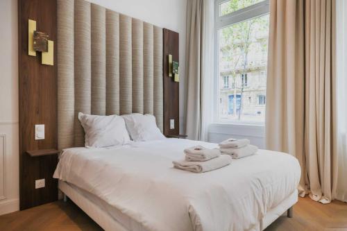 une chambre avec un lit blanc avec des serviettes dessus dans l'établissement Cosy flat - 1BR- 4P - Arc de Triomphe, à Paris