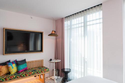 a living room with a television and a bench with pillows at Mama Shelter Lisboa in Lisbon