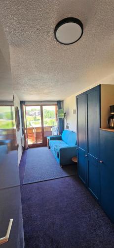 un salon avec un canapé bleu dans une pièce dans l'établissement Le balcon du soleil, Pied de pistes 2100m 5 pers Plagne Soleil paradiski classé 2 étoiles meublé et 3 cristaux Paradiski, à La Plagne Tarentaise