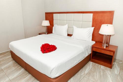 a white bed with a red flower on it at بروج السالمية للشقق المخدومة Brouj Al salmiya apartments Serviced in Dammam