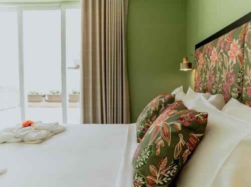 a bedroom with a white bed with a green wall at King Charles Hotel in Valletta