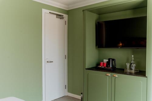 a kitchen with green walls and a door with a television at King Charles Hotel in Valletta