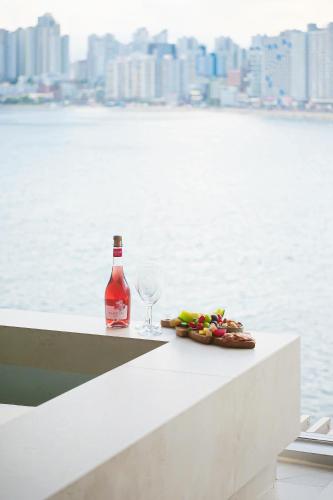 a bottle of wine and a plate of food and a glass at B'amu Hotel in Busan