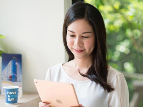 a woman is looking at a tablet computer at HOP INN Krabi Building A in Krabi town