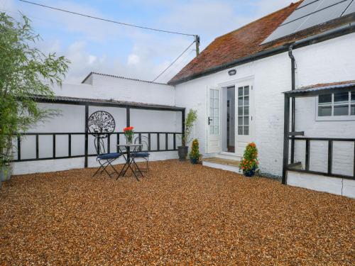a patio of a white house with a chair at Calvin's Cottage in Arundel