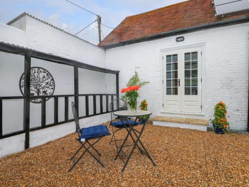 a table and two chairs in front of a white building at Calvin's Cottage in Arundel
