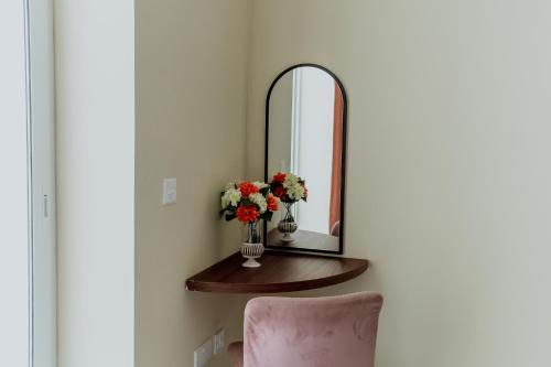 a mirror and a vase of flowers on a table at King Charles Hotel in Valletta