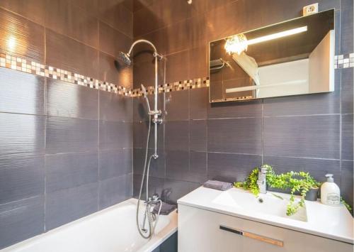 une salle de bain avec un lavabo, une baignoire et un miroir dans l'établissement Le Joinville Trend Home, à Joinville-le-Pont