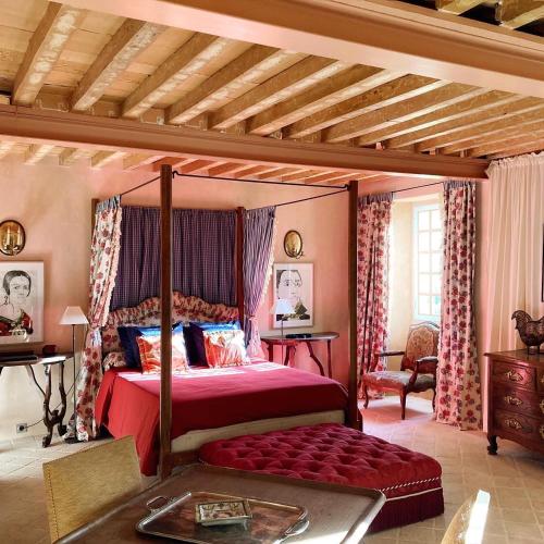 - une chambre avec un lit à baldaquin et un couvre-lit rouge dans l'établissement Magnifique Château d'Hémevez au coeur de la presqu'île du Cotentin, à Hémevez