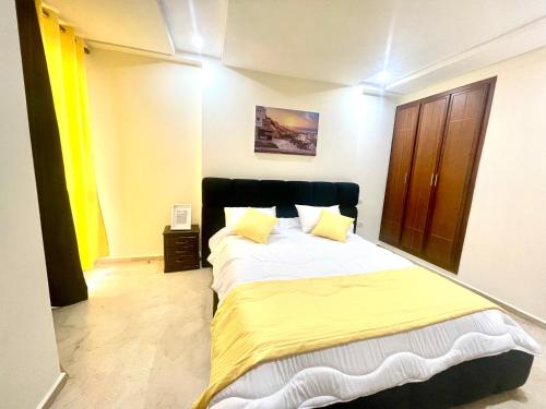 a bedroom with a large bed with yellow sheets at Family apartment in tangier in Souani