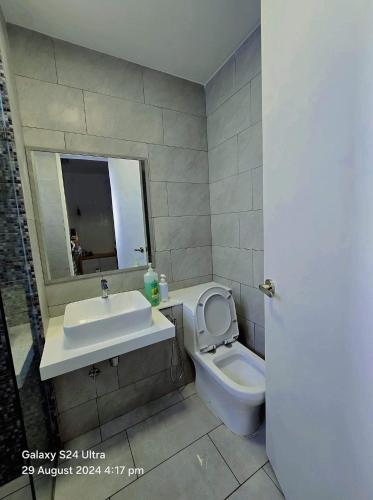 a bathroom with a sink and a toilet and a mirror at The Shore Home Suites Kota Kinabalu City Sabah Center in Kota Kinabalu