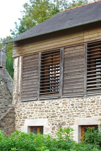 a stone building with two shuttered windows on it at Gite De La Tannerie 2 in Dinan