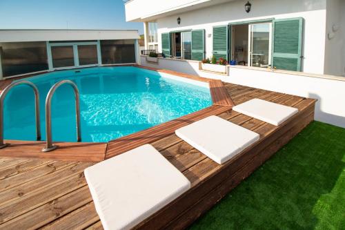 a swimming pool with a wooden deck and a house at LA CASA DEL SOLE - Beachfront B&B - Anzio in Anzio