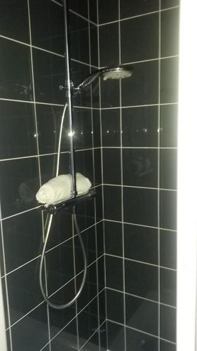 a black tiled shower with a shower head at Gite De La Tannerie 2 in Dinan