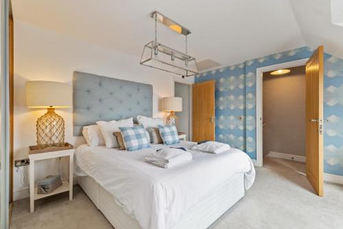 a bedroom with a white bed with a blue wall at Ger Y Mor - Village Centre with Parking in Saundersfoot