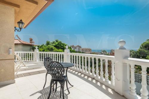 a table and two chairs sitting on a balcony at Grand villa with pool, BBQ & stunning view by REMS in Arroyo de la Miel