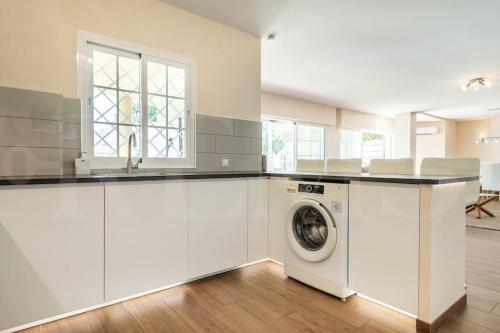a white kitchen with a washer and dryer at Grand villa with pool, BBQ & stunning view by REMS in Arroyo de la Miel