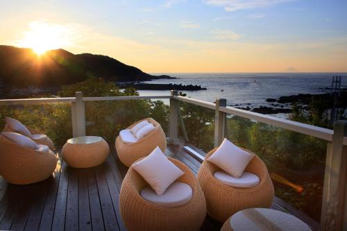 a deck with chairs and the ocean at sunset at Ocean View Hiromi SPA Hotel温泉と絶景の宿 in Shimoda