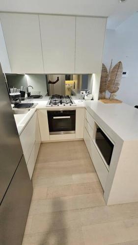 a kitchen with white cabinets and a stove top oven at Bondi Junction Bellissima in Sydney