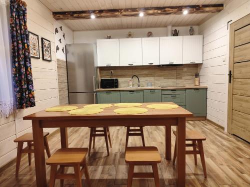 a kitchen with a table with chairs and a refrigerator at Wehikuł Czasu in Jędrzejówka