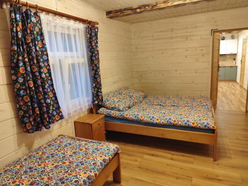 a bedroom with two beds and a window with curtains at Wehikuł Czasu in Jędrzejówka