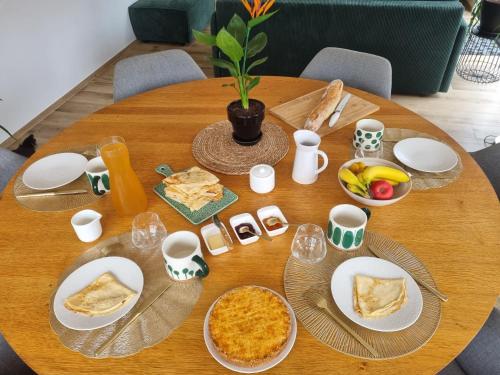 ein Holztisch mit Tellern voller Essen darauf in der Unterkunft Les Ganivelles in Belz