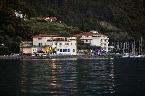 a large white building next to a body of water at Hotel Paradiso Conca d'Oro in Nago-Torbole